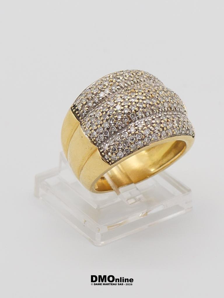 Gold ring with a diamond-pavé top on a clear display stand.