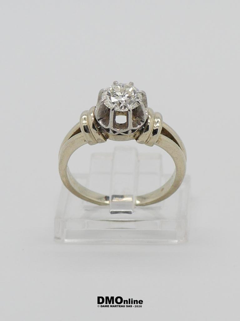 Two-tone engagement ring featuring a round diamond in a raised prong setting on a two-tone band, displayed on a clear stand.