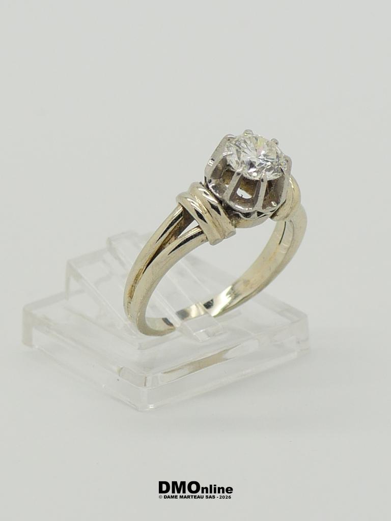 Diamond solitaire engagement ring with a round-cut diamond on a white-gold band, displayed on a clear stand.