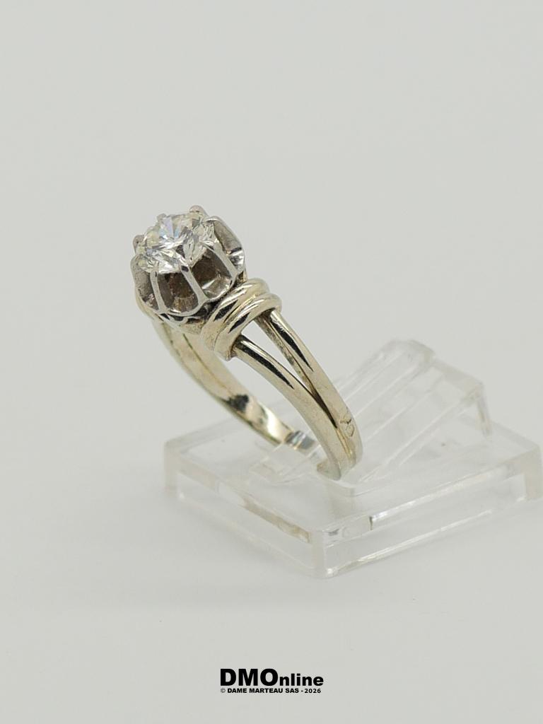 Silver ring with a round diamond solitaire in a prong setting on a clear display stand.