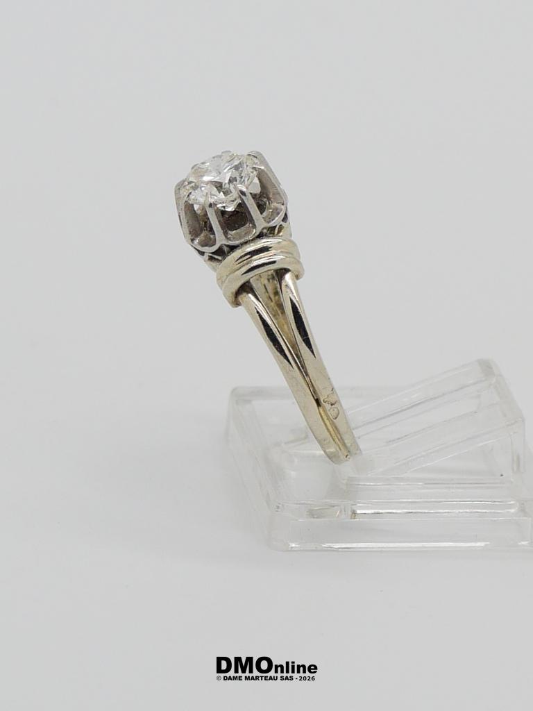 Diamond engagement ring in a metal prong setting on a clear display stand.