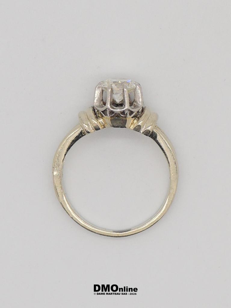 Two-tone engagement ring with a round diamond held by four prongs atop a gold band on a light background.