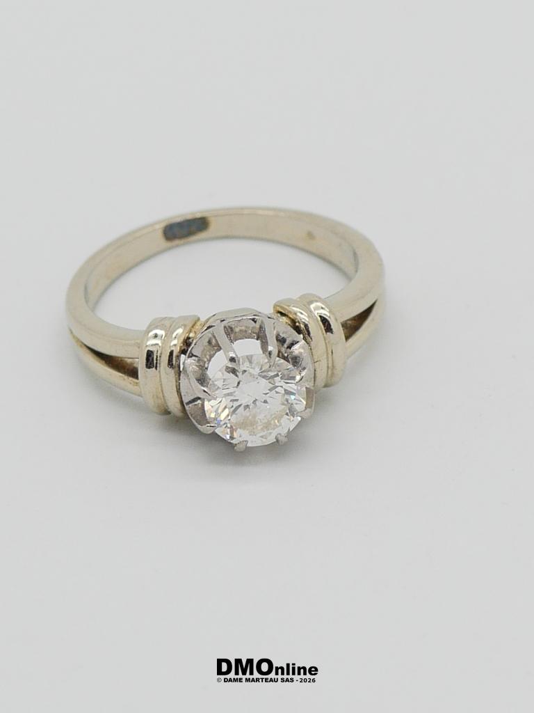 Engagement-style ring with a round clear diamond on a silver band against a white background, close-up view.