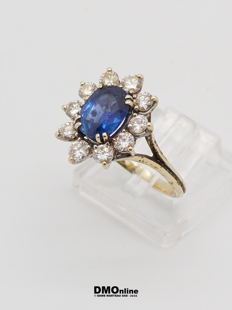 Gold ring with a deep blue oval sapphire center surrounded by a halo of diamonds on a slender band.