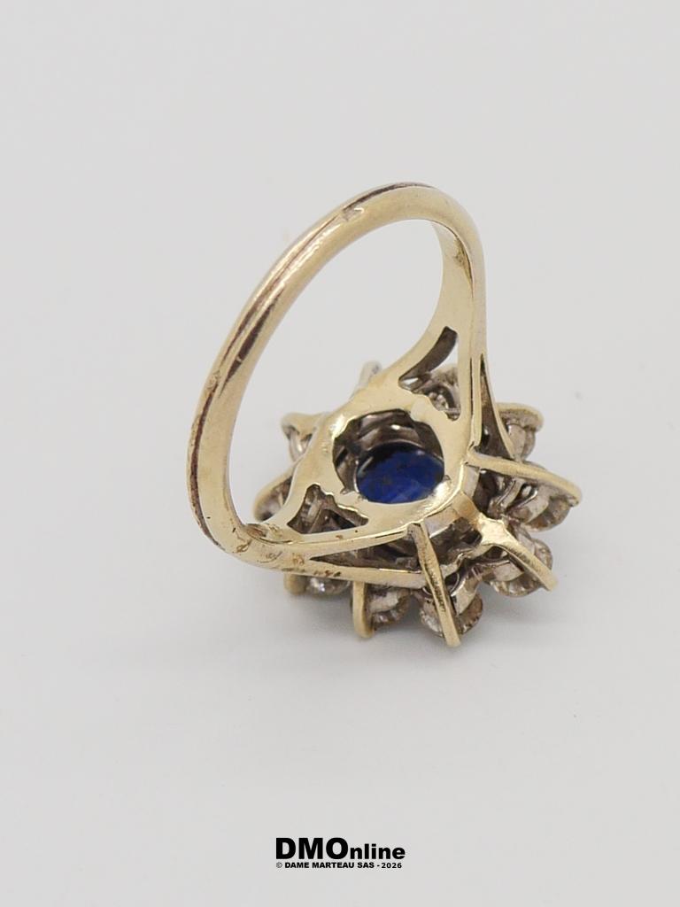 Gold ring with an intricate openwork setting and a blue gemstone at the center.