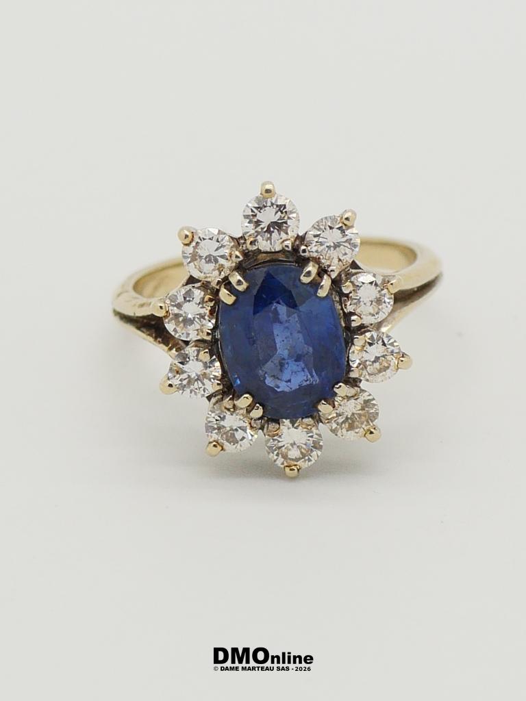 Gold ring with an oval blue sapphire centerpiece surrounded by a halo of diamonds in a flower-like setting.
