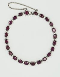 Silver chain necklace with alternating purple stones and small diamonds on a light background.