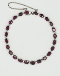 Silver chain necklace with alternating purple stones and small diamonds on a light background.
