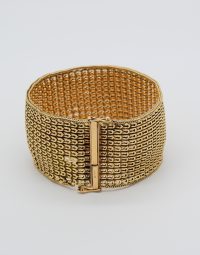 Gold-tone wide mesh bracelet with a hinged rectangular clasp on a light background, close-up view.