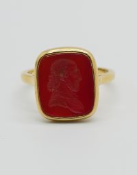 Gold ring with a red rectangular cabochon featuring a carved-profile cameo of a bearded man on a white background