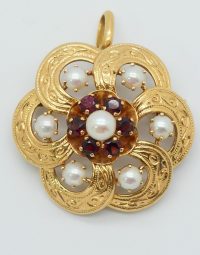 Gold floral pendant with central pearl surrounded by red gemstones and white pearl accents.
