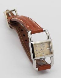 Vintage square-faced wristwatch with a brown leather strap and silver case.