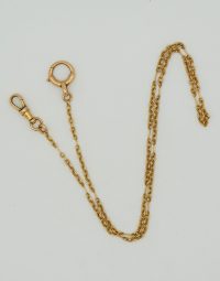 Gold chain necklace with a lobster clasp and circular ring on a pale background