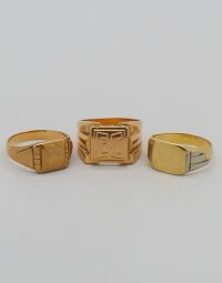 Three gold signet rings with square engraved faces on a white background.