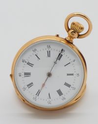 Gold pocket watch with white dial and Roman numerals, lying on its side on a pale surface.
