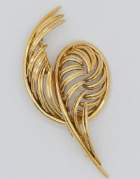 Gold-tone feather-shaped brooch with curved overlapping leaflets on a white background.