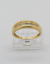 Gold ring with a row of diamonds along a central channel, displayed on a clear stand